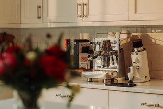 Professional espresso machine on a kitchen counter with a grinder and cookbooks nearby