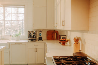 Bright white kitchen with a countertop coffee setup including an espresso machine and grinder
