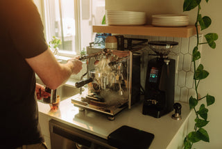 Barista inserts a portafilter into a high end chrome espresso machine in a modern kitchen