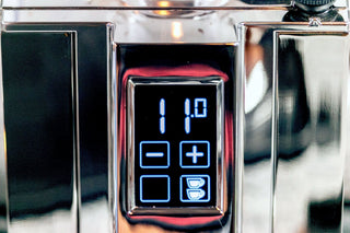Close up of an espresso grinder control panel with a blue digital readout and plus minus buttons