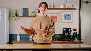 Talent with hands emphatically points to the left in front of an espresso machine lifestyle by Clive Coffee.