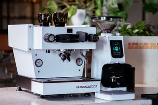 White La Marzocco espresso machine with a digital display and portafilter mounted on the group head