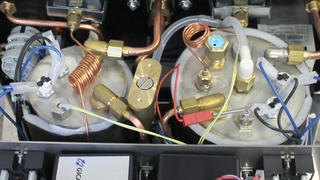 Close up of a commercial espresso machine internals showing copper tubes and fittings.