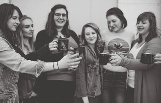 Women celebrate International Women's Day, toasting coffee mugs together