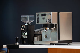 Rancilio Silvia Pro X espresso machine with stainless steel panels and digital display against a dark wall.