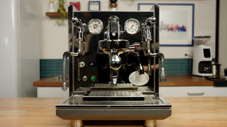 ECM dual group espresso machine with chrome finish, gauges, and portafilters on a countertop.