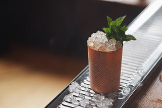 Copper cup filled with crushed ice and fresh mint on a bar counter