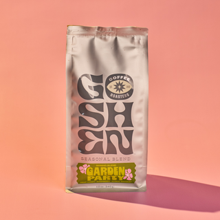 Garden Party coffee bag with bold orange and black graphic on a silver pouch against a peach background