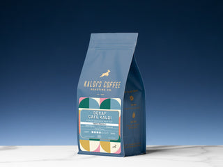 Kaldi's Decaf Cafe Kaldi coffee bag standing upright against a deep blue background.