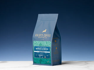 Blue Kaldi's Birds & Bees coffee bag photographed against a blue sky.