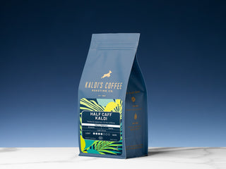 Kaldi's Coffee Half Caff bag on a display against a clear blue sky with colorful label art.