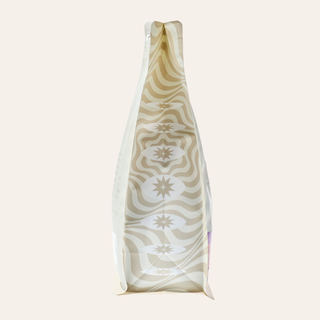 Close up of a bottle neck wrapped in cream patterned paper with a beige wave design.