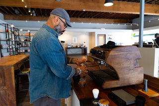 Barista in a denim shirt uses a professional espresso machine during a latte art class in a Portland cafe