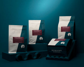 Colombian Decaf coffee bags stand against a teal backdrop.