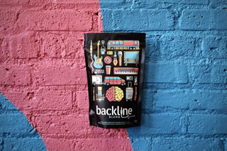 Backline Blend bag with colorful graphic design hanging on a pink and blue brick wall