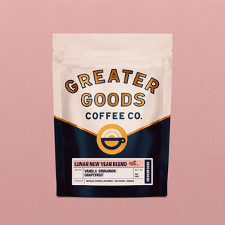 Front view of a Lunar New Year Blend bag from Greater Goods Coffee Co showing beige top panel and bold curved branding with a pink backdrop