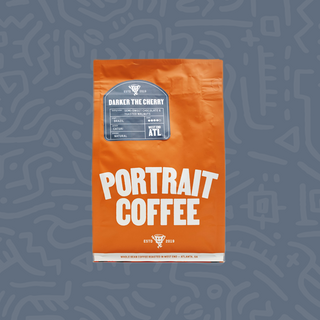 Orange Portrait Coffee bag featuring Darker the Cherry label on a blue backdrop.
