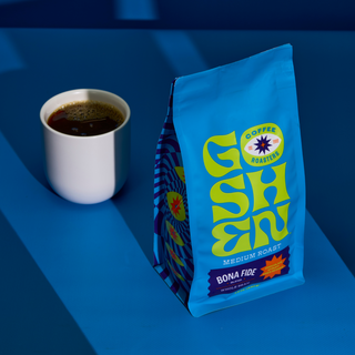 Goshen Coffee Bona Fide bag with a white mug of coffee on a blue surface
