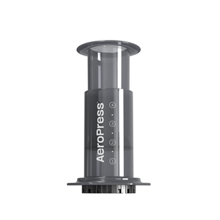 AeroPress coffee maker close up with the plunger partially extended and measurement marks on the dark gray body