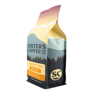 Sisters Coffee Black Butte Gold dark roast bag with pastel mountain landscape artwork