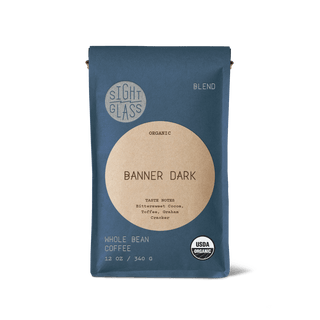 Banner Dark whole bean coffee bag in blue packaging with a beige circular label and Organic badge.