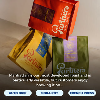 Colorful assortment of Partners coffee bags on a table including Manhattan green bag and red and yellow bags