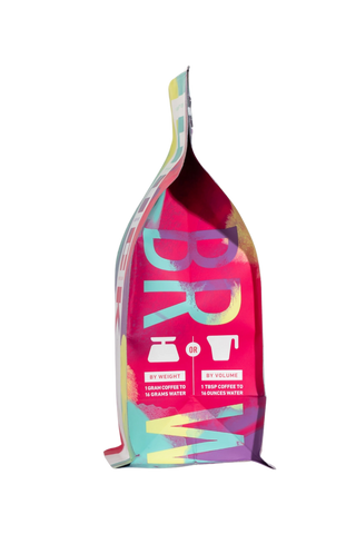 Side view of a vibrant multicolor coffee bag with abstract artwork and a folded top.