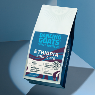Tilted white packaging card featuring a faint emblem and a blue Dancing Goats label