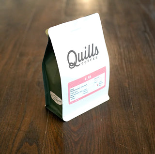 Close-up of a dark green bottle with a white label featuring script text on a wooden surface