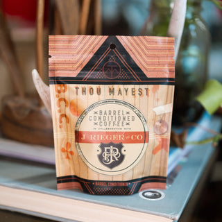 Barrel conditioned coffee packaging with copper geometric design on a display shelf