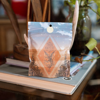 Boldly Go coffee bag with orange and blue geometric pattern on a wooden surface.