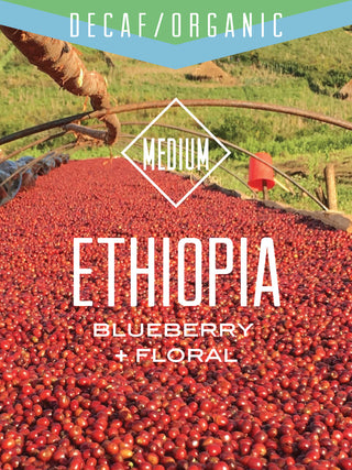 Decaf Organic Ethiopia bag front with blue banner and medium roast diamond over drying red coffee cherries.