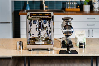 Polished ECM Technika VI dual boiler espresso machine on a kitchen counter with portafilter and gauges.