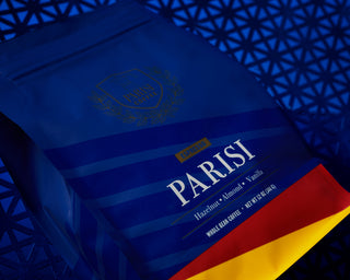 Blue tinted close up of a Parisi Espresso coffee bag with a gold seal against a blue background