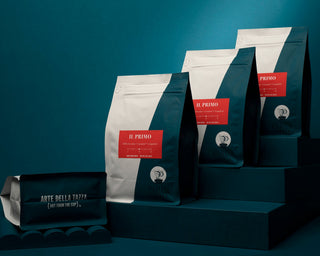Rows of Il Primo Parisi Coffee bags with red labels on a teal backdrop