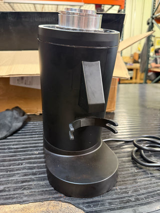 Side view of the DF83 single dose grinder with a chrome top and black body on a workbench