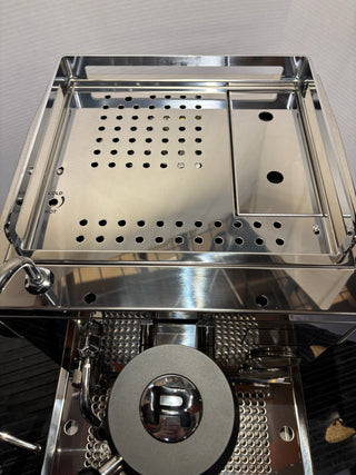 Interior of a stainless Rocket R Nine One espresso machine showing perforated drip tray and metal side panels