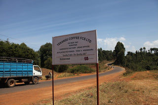 Tekangu Coffee FCS Ltd sign on a rural road with a truck and trees in the background