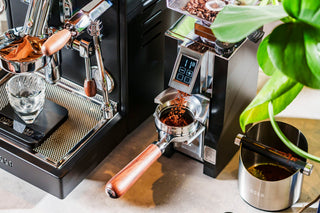 Lifestyle shot of LUCCA dosing funnel beside an espresso machine with a portafilter and ground coffee