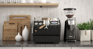 La Marzocco GS3 espresso machine on a kitchen counter with wood cutting boards and a grinder nearby