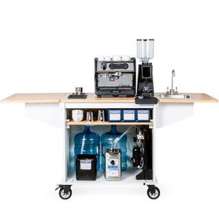 Mobile coffee cart with LUCCA espresso machine and grinder on a wooden counter cups on top and a sink on the right