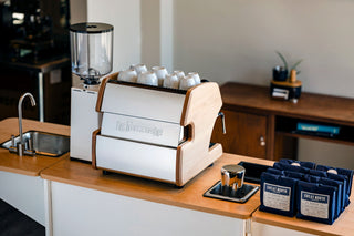 Klassy Karts turn-key mobile coffee cart featuring a white wood framed espresso machine with a row of white cups on top