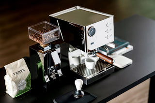 Front view of LUCCA Tempo espresso machine with two wooden portafilters and a clear bean hopper nearby.