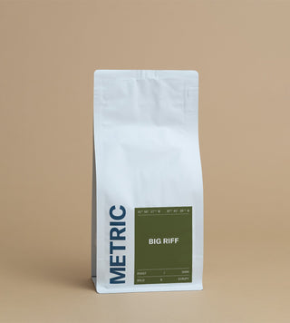 Big Riff coffee bag with a dark green label on a white standup pouch against a tan backdrop