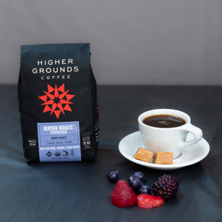 Mayan Magic Espresso dark roast bag with a cup of espresso and berries on a dark table