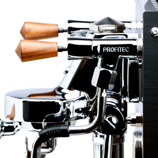 Close up of Profitec JUMP espresso machine showing wooden portafilter handles and a chrome body.