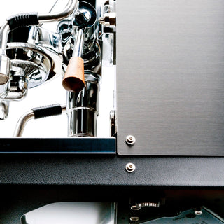 Chrome Profitec JUMP espresso machine close up with a copper toned wooden portafilter handle and brushed metal panel.