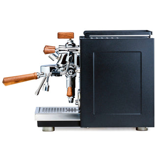 Side view of Profitec RIDE espresso machine with chrome group head and wooden knobs against a black cabinet.