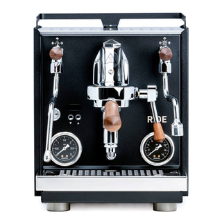 Close-up of Profitec RIDE dual boiler espresso machine showing two gauges and chrome portafilters with wooden handles.