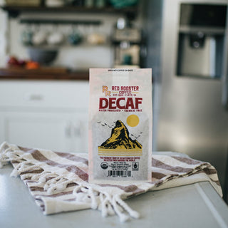 Organic decaf coffee bag upright on a striped kitchen towel in a kitchen
